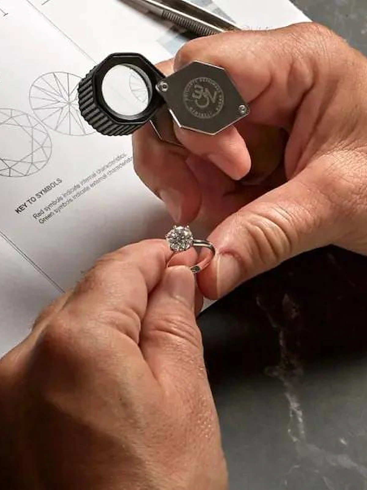 Un gemmologo esamina un anello con la lente